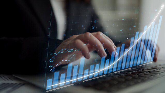 A business analyst focuses on data analysis using a laptop. Visual graphs and charts illustrate financial growth and performance metrics in a modern workspace environment. Copula