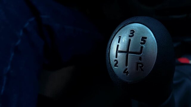 Close up of a manual gear shift lever inside a dark vehicle cabin from a different angle, driving controls, automotive interior, transportation concept.