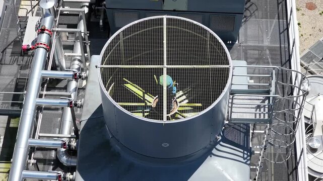 Aerial view of industrial cooling fan on a rooftop with metal piping and safety grating France.