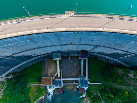 Aerial view of Barrage de Rossens showing the curved concrete wall, road on top, and water outlet structures in Pont-la-Ville, Fribourg, Switzerland.