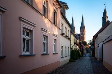 Fototapeta premium Historic cobblestone alley leading to church towers in Neuruppin, Brandenburg, Germany