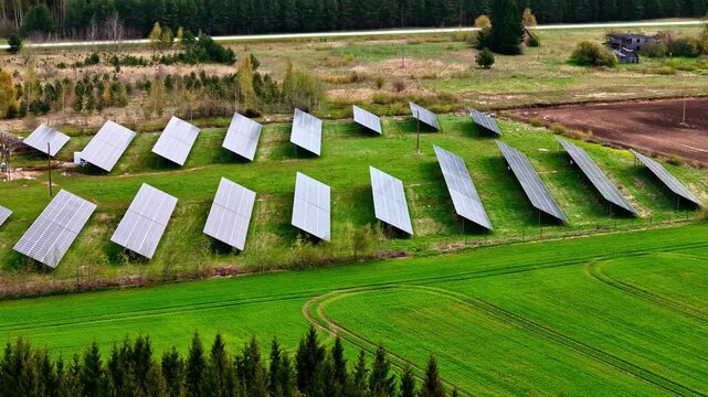 Aerial view of rows of solar panels installed on a green field in a rural landscape near Riga, Latvia.