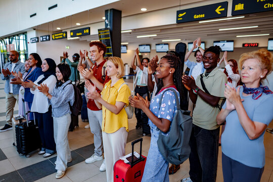 Diverse travelers applauding at airport terminal gates