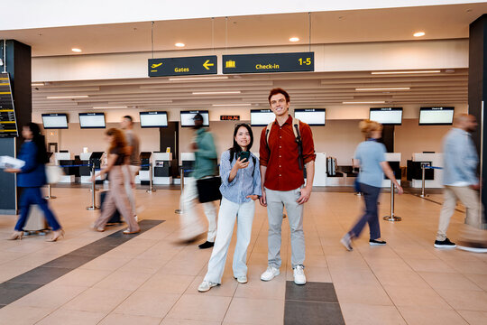 Young couple smiling at airport terminal check-in area