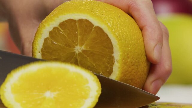 Extreme closeup of delicious orange being sliced with sharp knife