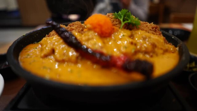 The dish features crispy fried cutlets chicken served on top of creamy scrambled eggs ("Kai Khon") and smothered in a rich, savory shrimp paste sauce.