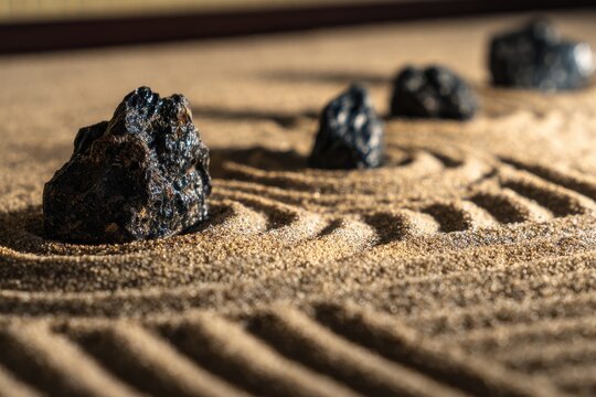 Zen garden with volcanic rocks and raked sand for meditation and relaxation in a studio setting; low angle shot
