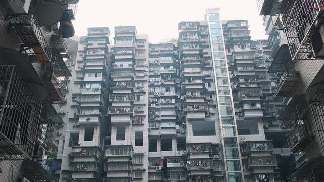 Residential apartment towers rising above narrow streets in Chongqing city, China. High-rise housing and compact urban development, vertical growth of megacity, residential architecture