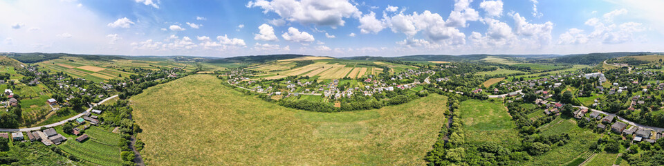 Fototapeta premium Aerial landscape view of green and yellow cultivated agricultural fields with growing crops on bright summer day