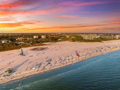 Aerial sunset view of Siesta Key beach in Sarasota, Florida with soft white sand and turquoise Gulf waters, crowds of tourists swimming, sunbathing and enjoying summer vacation.