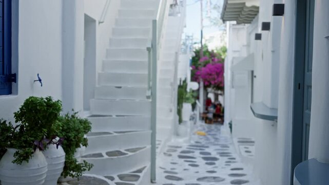 Mykonos narrow whitewashed alley in shallow bokeh with blurred stairs and pots; background backplate copyspace calm.