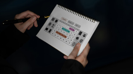 Detailed Close-Up of Hands Holding Open Sketchbook Featuring Colorful Chart and Icons on Pages in Dim Lighting. Glyphic. © InfiniteFlow
