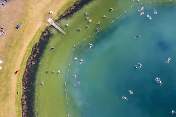 Overhead view of famous Florida Warm Mineral Springs in North Port, showing people swimming in circular lagoon, vibrant blue water and natural geological formation used for therapy. © bilanol