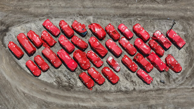 Aerial view of many new cars covered in red protective film parked in a dirt lot in Columbus, Ohio, United States.