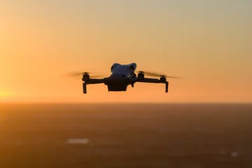 Small battery powered drone in flight above rural landscape, performing aerial survey and environmental monitoring with stabilized gimbal camera and autonomous navigation system. © bilanol