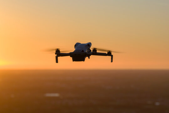 Small battery powered drone in flight above rural landscape, performing aerial survey and environmental monitoring with stabilized gimbal camera and autonomous navigation system.