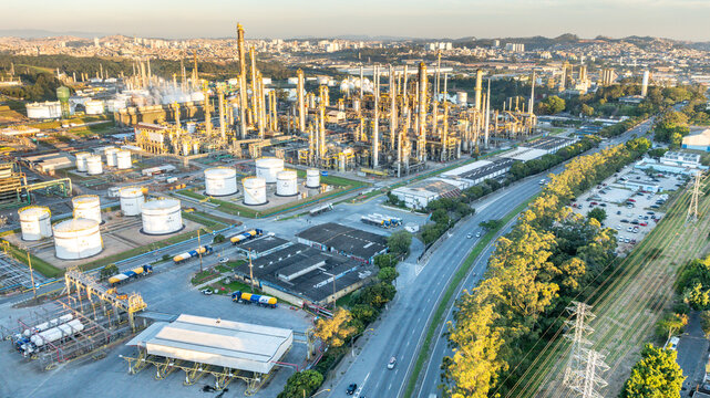 Aerial view of a large petrochemical complex with tall distillation towers and storage tanks situated near a highway in an urban industrial area in Santo Andre, State of Sao Paulo, Brazil.