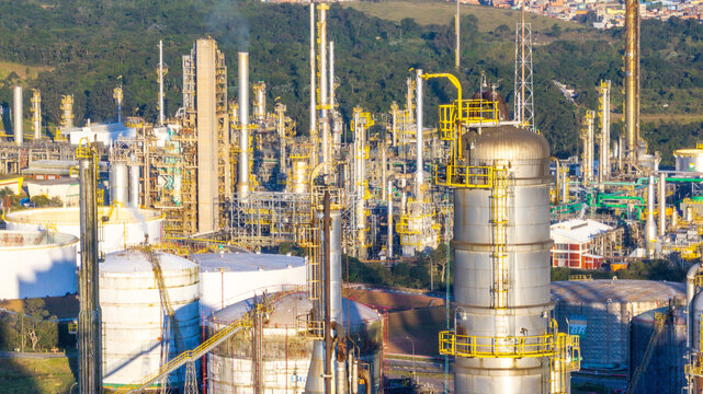 Aerial view of the petrochemical complex featuring tall industrial towers, storage tanks, and piping systems set against dense green vegetation in Santo Andre, State of Sao Paulo, Brazil.