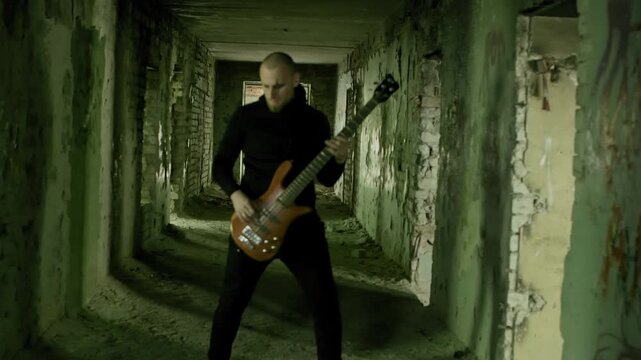 Man playing electric bass guitar in derelict hallway with crumbling walls, green tinted industrial decay setting conveying urban exploration, music creativity in forgotten spaces.