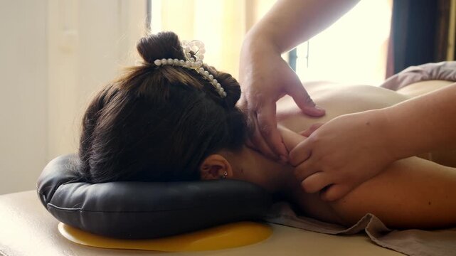 Professional massage therapist performs relaxing neck and shoulder massage for young woman. Wellness treatment promotes relaxation and muscle recovery.