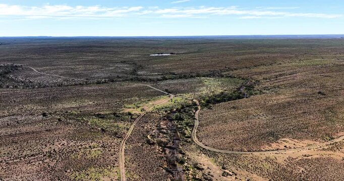 Drone view overlooking the vast semi-arid Karoo plains near Prince Albert in the Western Cape, South Africa. Dirt roads, shrubland, and distant horizons highlight the rugged beauty of the Great Karoo.