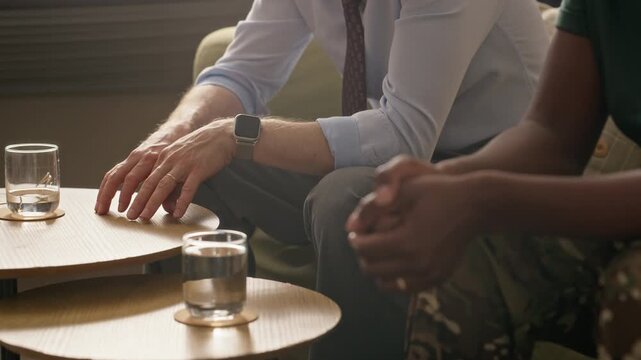 African American female soldier sitting with husband during counseling session, focusing on clasped hands. Ideal for veteran mental health support videos