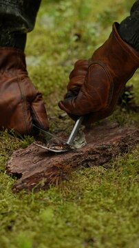 Close up of gloved hands striking sparks with a ferro rod and a knife to light a fire on birch bark. Concept of bushcraft skills, primitive fire making and wilderness survival.