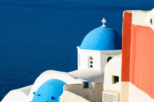 Blue‑domed churches rise above the Aegean Sea in Santorini, Greece, their whitewashed walls and vivid colors defining Cycladic beauty and spiritual charm.
