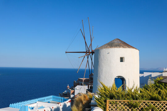 A traditional whitewashed windmill overlooking the deep‑blue Aegean Sea in Santorini, Greece &mdash; an iconic symbol of Cycladic architecture and coastal heritage.
