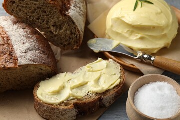 Fototapeta na wymiar Bread with homemade butter, salt and knife on grey wooden table, closeup