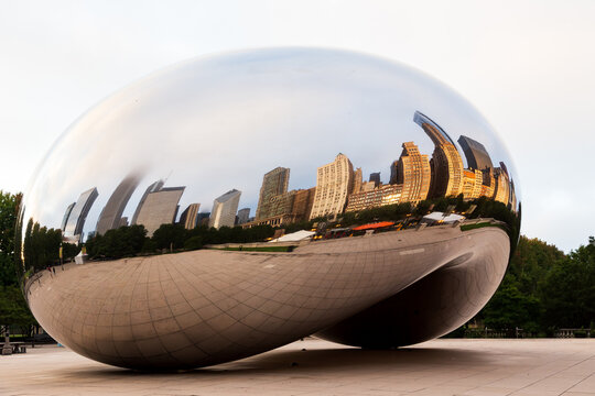 Chicago, Illinois, USA, October 1, 2024 - Side view of the 2006 Cloud Gate bean-shaped sculpture by Anish Kapoor in downtown Millennium Park seen at dawn, with reflection of buildings