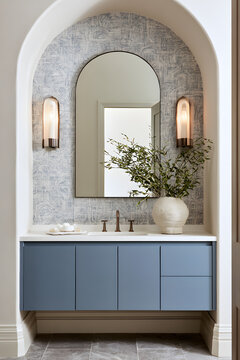 A bathroom vanity featuring dusty blue flat-front floating shelves, an arched mirror, wall lights, and a geometric wall texture, all within a contemporary decor scheme