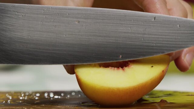 Juicy peach being sliced with large knife, extreme closeup shot