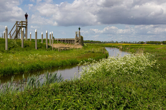 Schokland, Netherlands - 17 May 2015: View of the former harbor of Emmeloord with wooden poles and stairs under a cloudy sky.