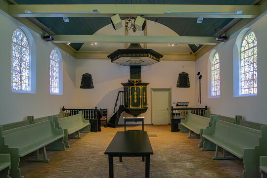 17 May 2015: View of the interior of a historic chapel featuring an ornate green and gold pulpit with a sounding board, rows of wooden pews, and arched windows under a vaulted ceiling.