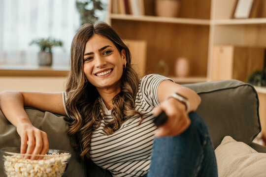Woman smiling while relaxing on sofa watching tv