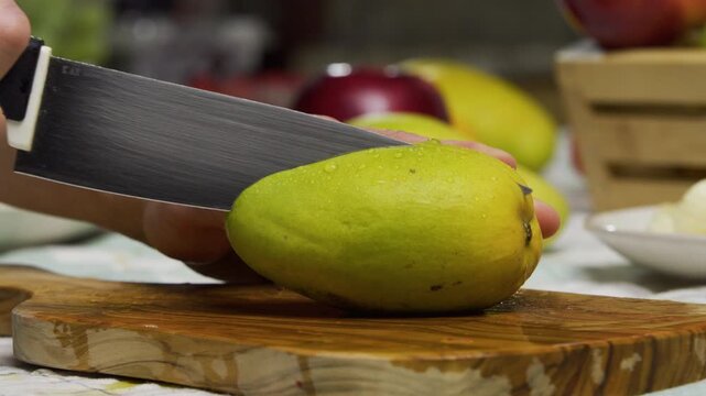 Large knife slicing through delicious mango on all ends - closeup shot