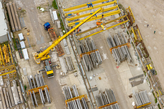 Aerial view of prestressed concrete elements production with a mobile crane lifting construction materials in a factory yard in Poland.