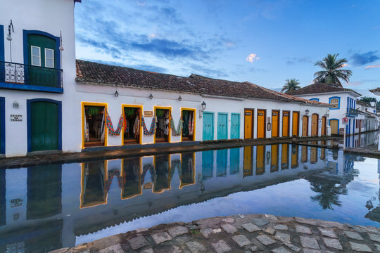 Paraty, Brazil - Historic colonial center street flooded by high tide seawater reflecting colorful traditional white houses with blue and yellow frames