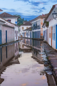 Paraty, Brazil - Historic colonial center street flooded by high tide seawater reflecting colorful traditional white houses with blue and yellow frames