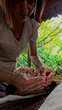 Professional masseur giving relaxing facial massage treatment outdoors