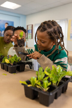 African youth with adults inspecting seedling using magnifier at workshop table over black tray