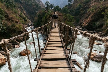Obraz premium Man Crossing a Rustic Rope Bridge Over a湍急河流
