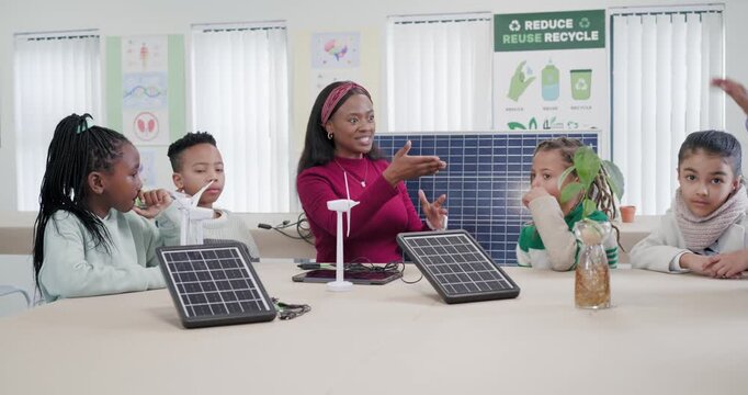 African American teacher pointing to solar panel, teaching renewables, inviting children to respond