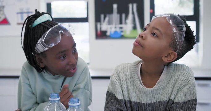 African American children whispering leaning over lab studying tray with goggles bottles to learn