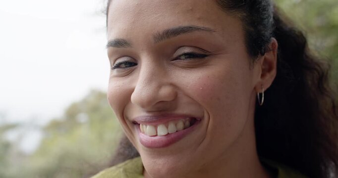 Adult African American woman smiling at camera after side glance on porch, green top, hoop earring