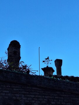 silhouette of a weathervane on the house roof top