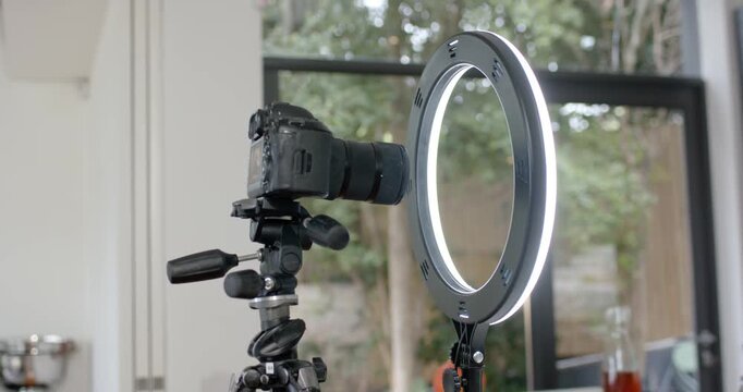 DSLR camera and LED ring light are being adjusted by off-screen operator for window-lit table shoot