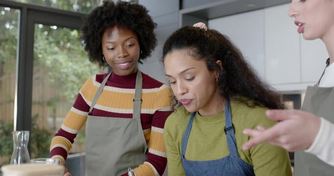 Diverse women watching right woman pointing, center whisking in bowl, ring light DSLR filming demo