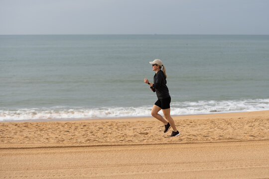 Young woman in shorts running on the beach. Girl runs to the coast, sports lifestyle